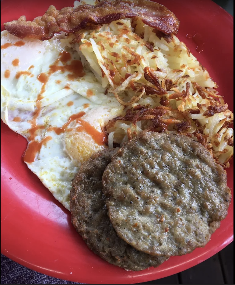 Two eggs, hash browns, bacon and sausage on a red plate