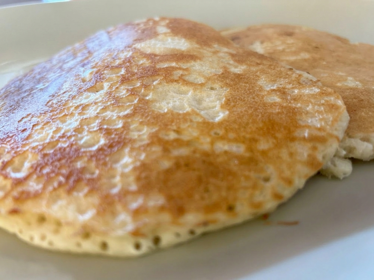 A tall stack of thick buttermilk pancakes with butter
